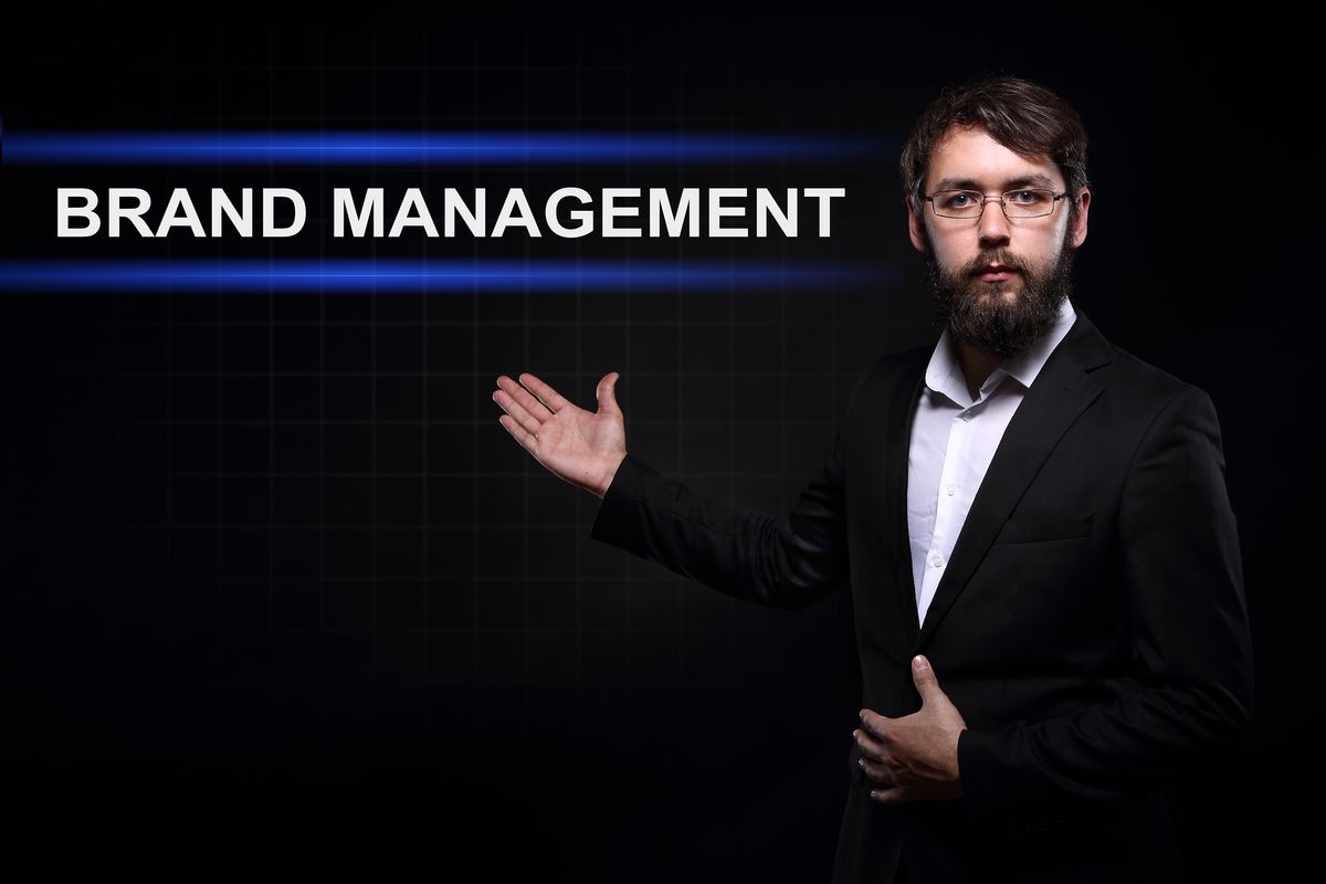 Businessman over black background presenting Brand management